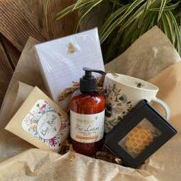Bee-themed gift box with lotion, mug, notepad, seed packet, and small honeycomb item.