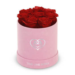 Red roses arranged in a pink round box with a heart logo