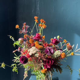 Mixed bouquet of burgundy roses and orange flowers in a glass vase