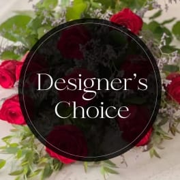 Red roses with greenery and filler flowers around a "Designer’s Choice" label
