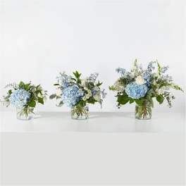 Three blue and white floral arrangements in clear glass vases