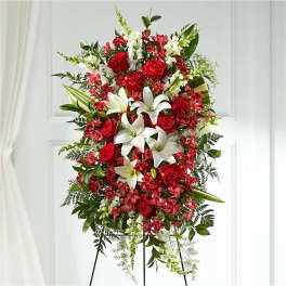 Standing floral spray with red roses and white lilies on a black easel
