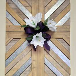 White flowers with a purple ribbon on a geometric wood wall hanging