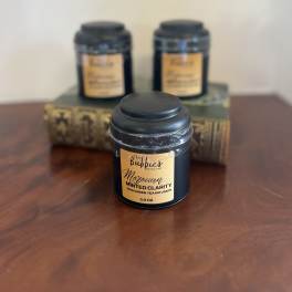 Black tea tin with gold label on a wood surface, with two similar tins blurred behind on stacked books.