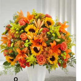 Orange and yellow mixed flower arrangement in a white vase
