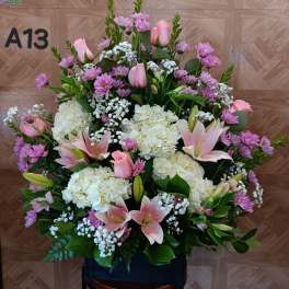 Large pink and white floral arrangement with lilies, roses, hydrangeas, and purple daisies