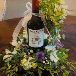 Wine bottle surrounded by a floral wreath on a table