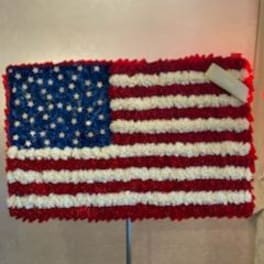 Floral arrangement shaped like the U.S. flag on a stand