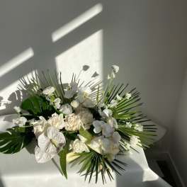 White floral arrangement with orchids and roses on a table