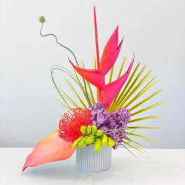 Bright tropical floral arrangement in a ribbed white vase