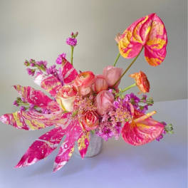 Pink and orange floral arrangement in a small gray vase