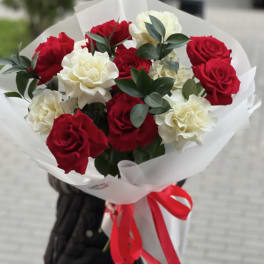 Bouquet of red and white roses wrapped in white paper with a red ribbon