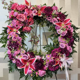 Large circular floral wreath with pink and purple flowers on a stand