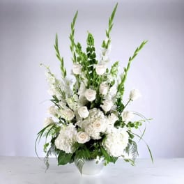 Tall white floral arrangement in a white vase with roses and lilies