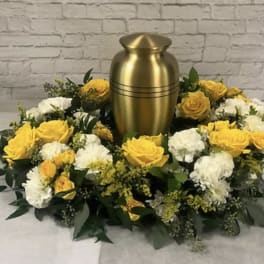 Yellow and white rose wreath around a gold urn