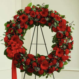 Large red floral wreath on a black stand with a ribbon