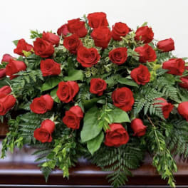Large arrangement of red roses with greenery on a casket