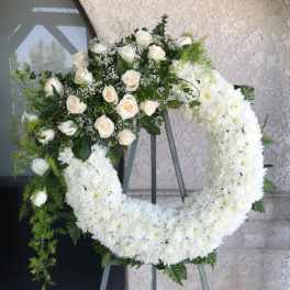 White floral funeral wreath on a standing easel with roses and chrysanthemums