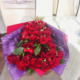 Large bouquet of red roses wrapped in purple paper