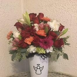 Mixed bouquet of red, pink, white, and orange flowers in a white vase