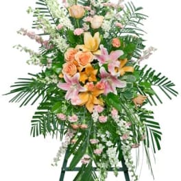 Tall pastel standing spray with lilies, roses, and carnations on a green easel