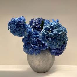 Blue hydrangea arrangement in a gray vase