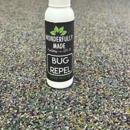 A white spray bottle labeled bug repellent stands on a carpeted floor.