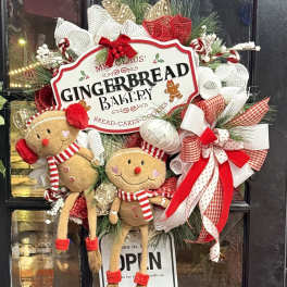 Christmas wreath with gingerbread figures and red-and-white ribbons on a door