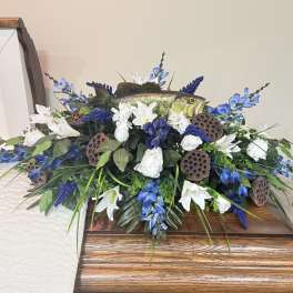 Blue and white floral arrangement with a fish centerpiece on a casket