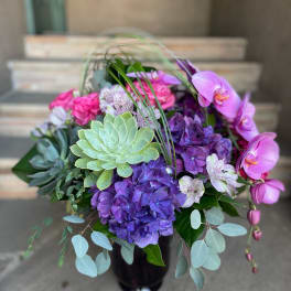 Bouquet of purple hydrangeas, pink orchids, and succulents in a vase