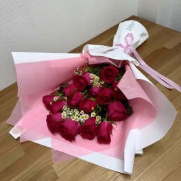 Bouquet of red roses wrapped in pink and white paper with a ribbon