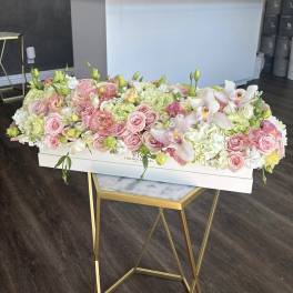 Long pastel floral arrangement in a white box with pink roses and white orchids