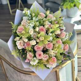 Bouquet of pink and cream roses with green orchids and white filler flowers