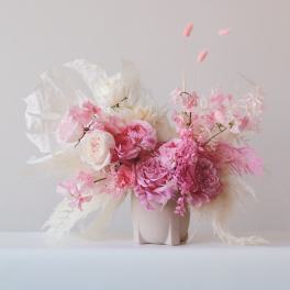 Pink and white floral arrangement in a pale vase