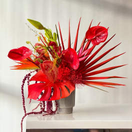 Bold red tropical floral arrangement in a striped vase