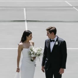 Bride holding a white bouquet beside a groom in a tuxedo