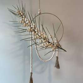 Abstract hanging wall decor with beads, grass-like stems, and a metal ring