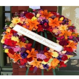 Large colorful funeral wreath with a white memorial ribbon