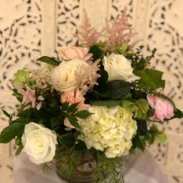 Bouquet of white and blush roses with pale green hydrangea in a vase