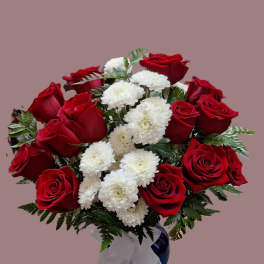 Arrangement of red roses and white mums in a blue vase with a white bow