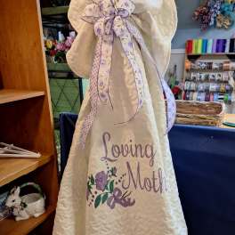 Quilted white hanging with a purple floral bow and "Loving Mother" text