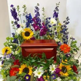 Colorful floral spray surrounding a red casket