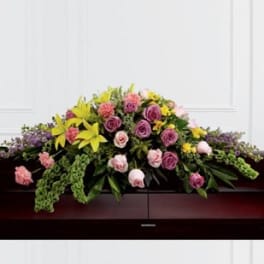 Casket spray with pink and purple roses and yellow lilies