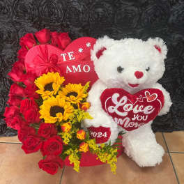 Red roses and sunflowers arranged with a white teddy bear and heart decorations