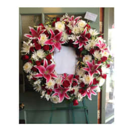 Heart-shaped funeral wreath with pink lilies, red roses, and white flowers