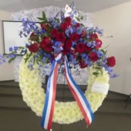 Red and blue floral wreath on an easel with ribbon streamers