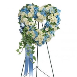 Heart-shaped floral wreath on a stand with blue and white flowers
