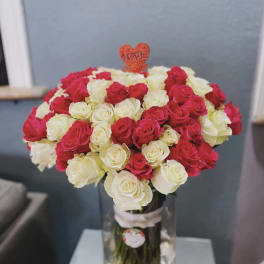Bouquet of red and white roses in a clear vase with a heart topper
