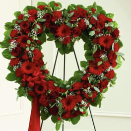 Heart-shaped red floral wreath on a stand with a ribbon