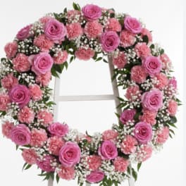 Pink rose and carnation wreath with baby's breath on a white stand
